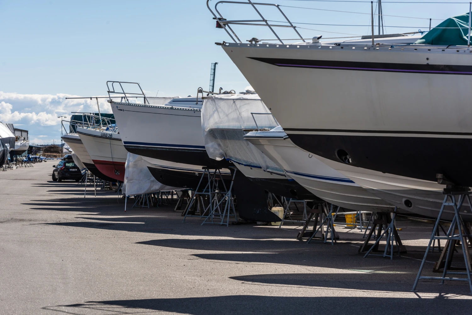Long row of sailboats laid up at a parking lot.